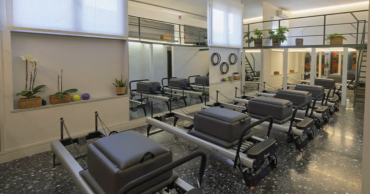 Istruttore Pilates guida una lezione Reformer in studio